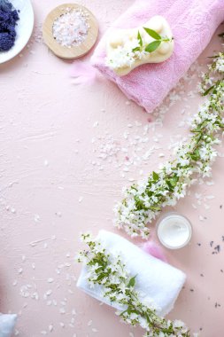 Spa. Havlu, deniz tuzu ve sabun. Pembe bir arka plan ve çiçekler. Metin için yer. Dikey fotoğraf.
