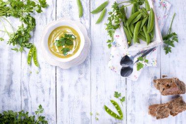 Yeşil bezelye ve maydanoz krem çorbası. Beyaz ahşap zemin, kopya alanı üzerinde beyaz bir tabak içinde sağlıklı öğle yemeği