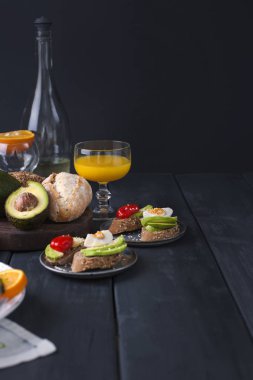 Avokado, yumurta ve domates, siyah ahşap zemin ile tost. Suyu ve beyaz şarap, lezzetli yiyecek öğle yemeği için. Kopya alanı