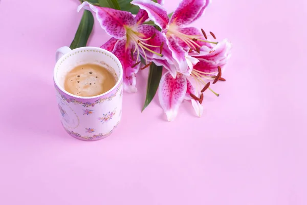 Fundo rosa, xícara de café da manhã e um buquê de flores de lírios. Espaço livre para texto. Flat lay, espaço de cópia — Fotografia de Stock