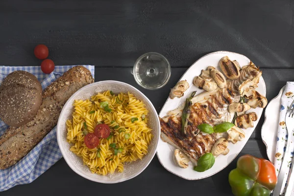 Cibo diverso su un tavolo nero, vista dall'alto. Pasta, pane fresco ai cereali, pesce alla griglia e insalata. copiare spazio. posa piatta — Foto Stock