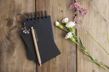 Notlar ve çiçekler için not etmek. Ahşap arka plan. Metin için yer,