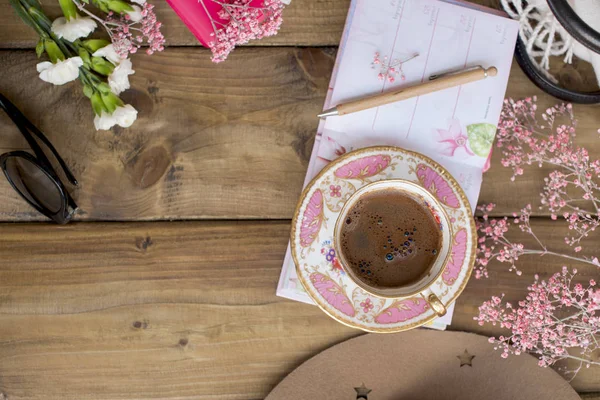 Café fragrante preto, flores e copos. Bom dia, cores ensolaradas. Acessórios femininos e bloco de notas com uma caneta. Planejamento. Atmosfera acolhedora — Fotografia de Stock