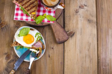 Yumurta ve pastırma ve fesleğen tost. Kahve ve bir bardak su. Kahvaltı. Ahşap arka plan ve metin için yer. Yukarıdan görüntülemek,