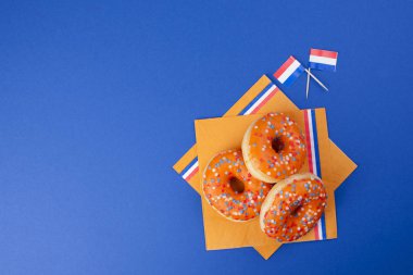 Kings günü kutlama Hollanda. Eğlenceli tatil. Mavi bir arka plan ve bayrakları turuncu tatlı donats. Metin için özgür yer. Sivol tatil,