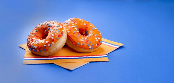 Célébration de la fête des rois aux Pays-Bas. Des vacances amusantes. Donats sucrés orange sur fond bleu. Espace libre pour le texte — Photo