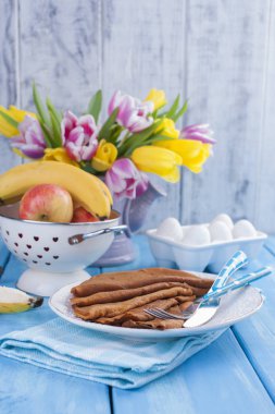 bir buket sarı ve pembe ve çiçek ve krep taze lale. Mavi arka plan. Bahar. Meyve bir vazo içinde. Metin için boş alan.