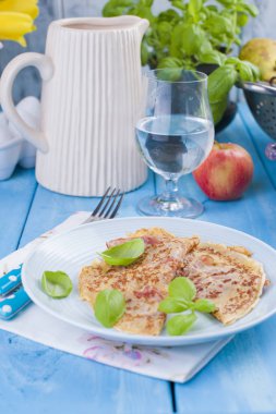 Hollandalı krep ile jambon kahvaltı için. Parlak renkler, mavi arka plan. Lezzetli ve kalori. Bir bardak su ve bir şişe şarap. Metin için boş alan.