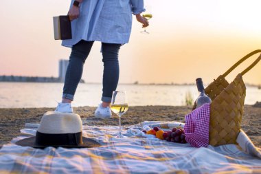 Denizin kenarında kumsalda romantik piknik. Bir bardak şarap el ve günbatımı kızla. İyi bir hafta sonu. Kopya alanı