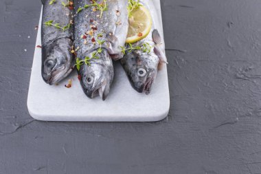 Çiğ balık. Alabalık limon ve beyaz bir taş gemide baharat. Gri arka plan. Metin için özgür yer. kopya alanı. düz lay