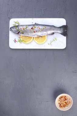 Çiğ balık. Alabalık limon ve beyaz bir taş gemide baharat. Gri arka plan. Metin için özgür yer. kopya alanı. düz lay.