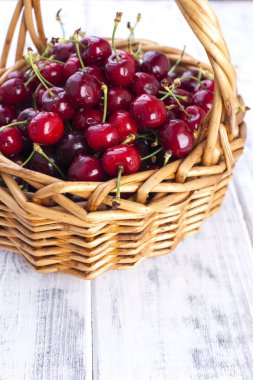 Olgun kiraz büyük bir sepet. Lezzetli ve tatlı çilek. Beyaz ahşap zemin, metin için özgür yer. Kopya alanı.