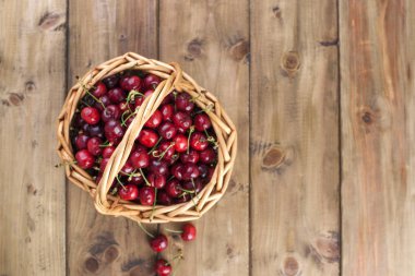 Olgun kiraz büyük bir sepet. Lezzetli ve tatlı çilek. Ahşap arka plan, metin için özgür yer. Retro tarzı. Uzay kopyalayın. Düz yatıyordu