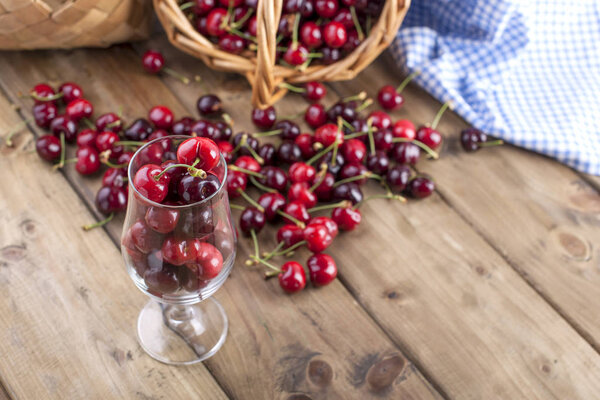 A lot of ripe and sweet cherries, on the table and in a glass, for traditional Belgian beer. Delicious red berries. Copy space