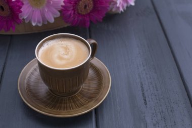 Sabah hoş kokulu kahve bir fincan, siyah ahşap arka plan ve bir buket pembe çiçek. Kopya alanı.