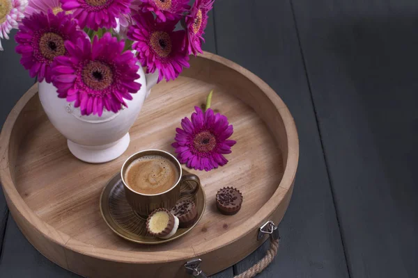 Delicious milk chocolate, a bouquet of fresh flowers and a morning aromatic coffee. Black wooden background, free space for text. Copy space.