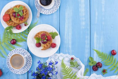 Çilek, çilek ve vişne ile küçük turta. Lezzetli tatlı kahvaltı ve hoş kokulu kahve, mavi ahşap arka plan üzerinde. Yukarıda. Yat, alanı Kopyala