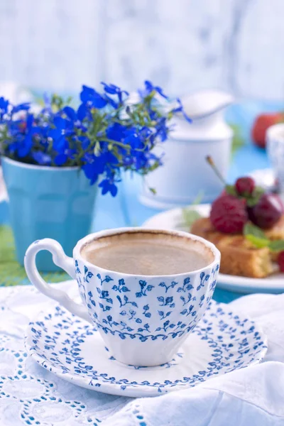 Çilek, çilek ve vişne ile küçük cupcakes. Lezzetli tatlı kahvaltı ve hoş kokulu kahve, mavi ahşap arka plan ve çiçekler. Kopya alanı.