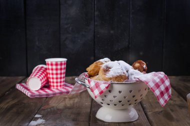 Ev yapımı kızarmış topları ile pudra şekeri. Peçete kırmızı kafes ve cam. Kahverengi ahşap arka plan. Amerikan pişirme.