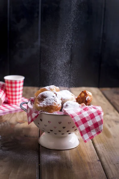 Ev yapımı kızarmış topları ile pudra şekeri. Peçete kırmızı kafes ve cam. Kahverengi ahşap arka plan. Hollanda pişirme.