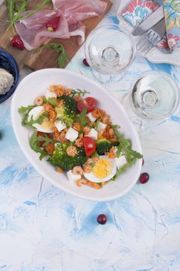 Tatil yemek. Sebze, karides, yumurta salatası. İki bardak şarap. Masa lambası.