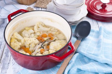 Karnabahar pişmiş kırmızı bir dökme demir ve büyük bir kaşık. Mavi havlu. Metin için özgür yer. Aile yemeği. Sebze