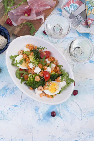 Tatil yemek. Sebze, karides, yumurta salatası. İki bardak şarap. Masa lambası.