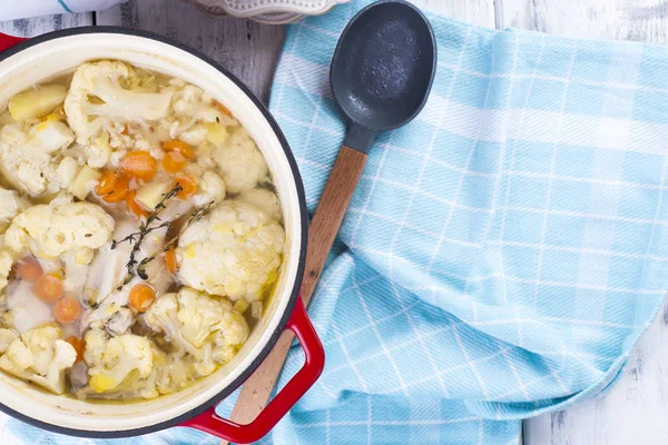 Karnabahar kırmızı bir dökme demir pişmiş. Mavi havlu. Metin için özgür yer. Aile yemeği. Hafif yiyecekler. Sebze.