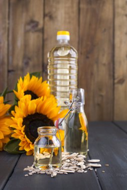 Ayçiçek yağı ve büyük sarı çiçekler. Petrol şişe. Ahşap arka plan ve Ayçiçeği çekirdeği. Organik gıda. Kopya alanı.