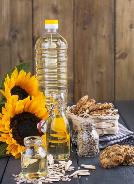 Ayçiçek yağı ve büyük sarı çiçekler. Petrol şişe. Ahşap arka plan, tohumlar ve fındık ve tohum ile bisküvi. Organik gıda. Kopya alanı