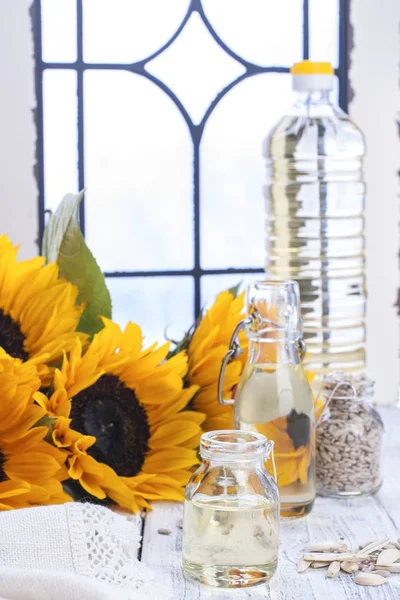 Ayçiçek yağı ve büyük sarı çiçekler. Petrol şişe. Ayçekirdeği kabuğu. Beyaz ahşap pencere arka plan. Vintage Fotoğraf. Organik gıda. Kopya alanı