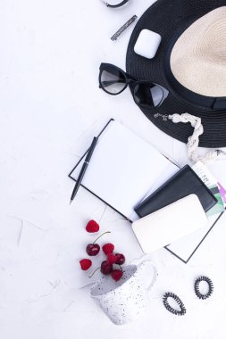 Bayan aksesuarlar, Not defteri girişleri, telefon ve pasaport için. Şapka ve güneş gözlüğü. Kupası ve çilek. Tatil. Beyaz arka plan. Uzay kopyalayın. düz lay