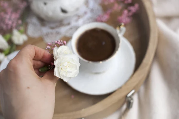 Женские руки держат белый цветок и розовый. Завтрак в постель. Ароматный кофе. Нежные светлые цвета. Романтика. Место для текста . — стоковое фото