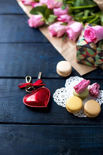 Un bouquet de roses et de biscuits comme cadeau pour une journée d'amoureux sur un fond noir et un cœur rouge . — Photo