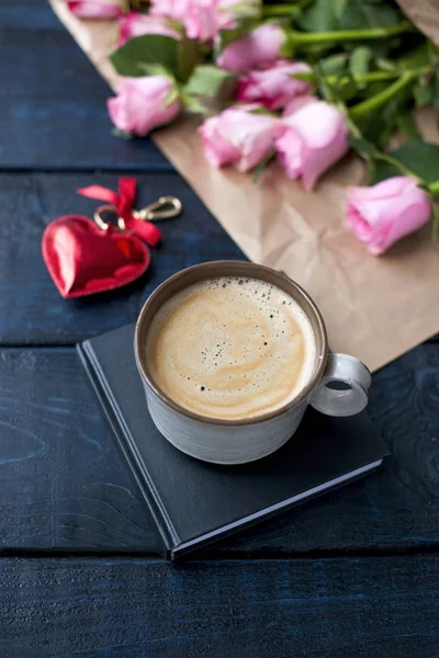 Una taza de café está en el libro. Ramo de rosas. Corazón rojo. Un regalo el día de San Valentín. Un lugar especial para el texto . — Foto de Stock