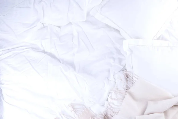 Top view bed with crumpled bed sheet, Good morning after a comfortable sleep. White pillow and blanket. Copy space