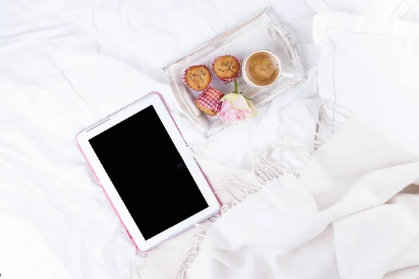 white bed, tablet computer, fresh coffee, breakfast cakes and Pink roses. Good morning Vintage photo. Copy space