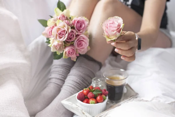 Букет розовых роз в руках девушки на кровати, ягоды клубники и ароматный утренний кофе. Романтика. Vintage фото. Копирование пространства — стоковое фото