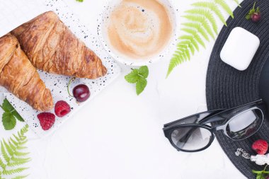 Bayan aksesuar, Bayan tatilde. Güneş gözlüğü ve şapka, kruvasan ve kahve kahvaltı için. Beyaz arka plan. Uzay kopyalayın. Düz yatıyordu