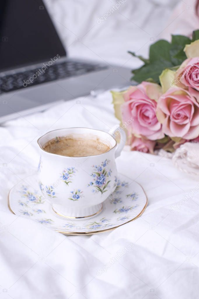 A bouquet of pink roses in the bed, a computer and a morning aromatic coffee. Copy spase