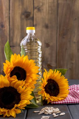 Şişe, bir buket ayçiçeği, terned bir arka plan ve dağınık tohum petrol dodsolnechnoe. Doğal ürün, rustik tarzı. Kopya alanı