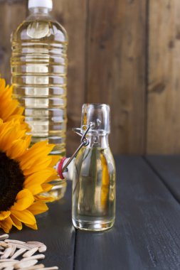 Dodsolnechnoe yağda bir büyük ve küçük bir şişe, bir buket ayçiçeği, küçük bir arka plan ve dağınık tohumları. Doğal ürün, rustik tarzı. Kopya alanı