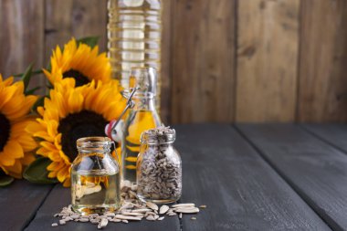 Dodsolnechnoe yağda bir büyük ve küçük bir şişe, bir buket ayçiçeği, küçük bir arka plan ve dağınık tohumları. Doğal ürün, rustik tarzı. Kopya alanı