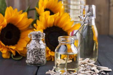 Dodsolnechnoe yağda bir büyük ve küçük bir şişe, bir buket ayçiçeği, küçük bir arka plan ve dağınık tohumları. Doğal ürün, rustik tarzı. Kopya alanı