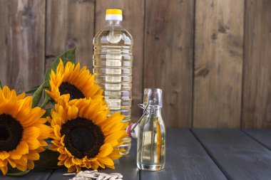 Dodsolnechnoe yağda bir büyük ve küçük bir şişe, bir buket ayçiçeği, küçük bir arka plan ve dağınık tohumları. Doğal ürün, rustik tarzı. Kopya alanı