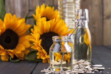 Dodsolnechnoe yağda bir büyük ve küçük bir şişe, bir buket ayçiçeği, küçük bir arka plan ve dağınık tohumları. Doğal ürün, rustik tarzı. Kopya alanı