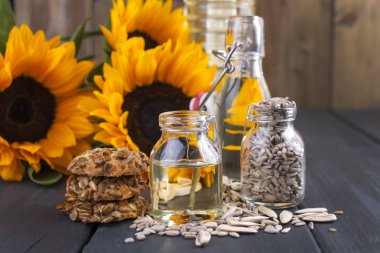 Dodsolnechnoe yağ bir şişe bir büyük ve küçük, deryl arka plan ayçiçeği çiçek bir buket. Bisküvi tohumları ile. Doğal ürün, rustik tarzı. Kopya alanı