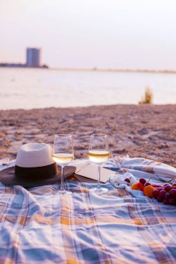 Denizin kenarında plajda şarapla piknik. Gün batımında romantik akşam yemeği. Kopya alanı