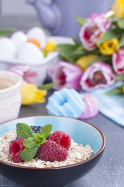 Tatlı aromalı kahve ve çilek ile müsli ile kahvaltı. Taze bahar çiçekleri. Sarı ve Pembe lale. Renkli yumurta Paskalya için