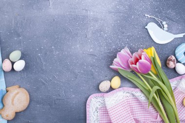 Gri beton zemin ve buket pembe laleler ve bisküvi. Paskalya dekor ve yumurta. Pembe havlu. Metin için boş alan